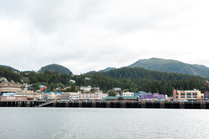 Coastal town with colorful buildings and forested hills in the background.