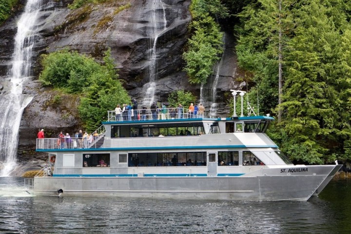 a boat traveling along a river next to a waterfall