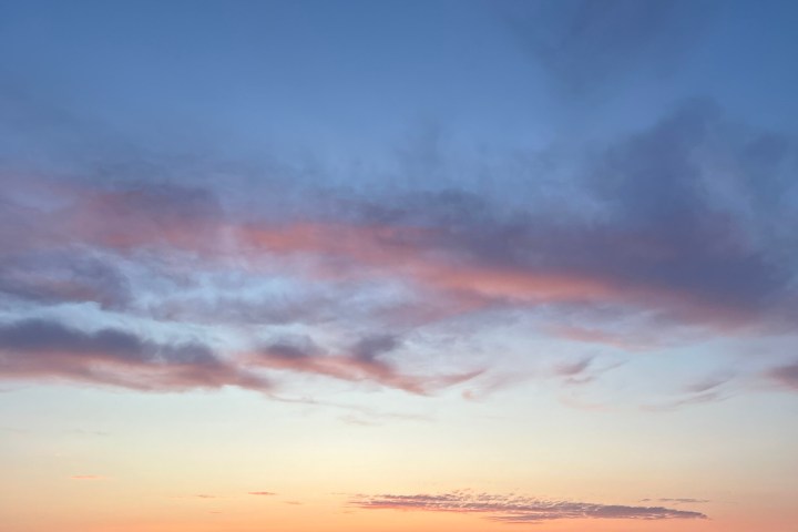 Sunset over ocean with clouds and distant mountains.